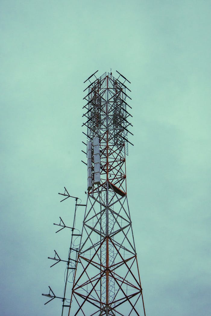 A tall communications tower with antennas reaching into a cloudy sky, symbolizing modern technology.